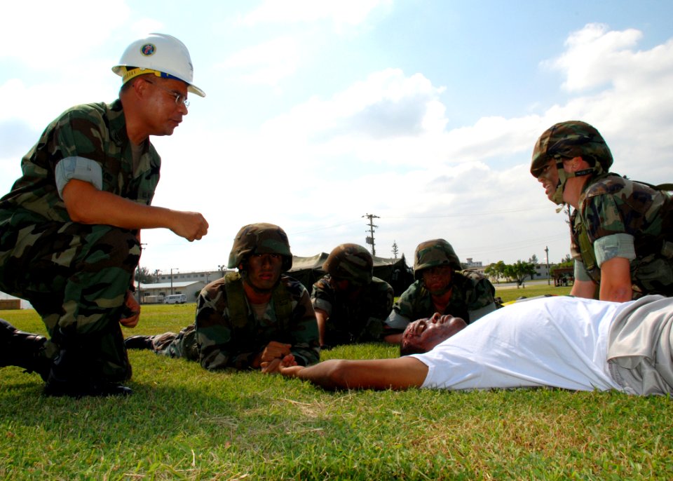 US Navy 071022-N-1120L-035 Capt. Robert Alonso listens as Engineering Aide Gayle St. Michel explains the process for beginning life-saving procedures on a simulated injured service member during a mass casualty drill