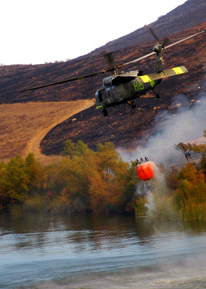 US Navy 071023-N-3069F-041 An MH-60S Seahawk assigned to Helicopter Sea Combat Squadron (HSC) 85, lifts a full 420-gallon extinguishing trough from a local reservoir near the raging wildfires in San Diego County