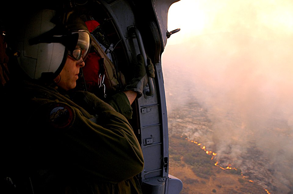 US Navy 071023-N-3069F-001 Chief Aviation Electronics Technician Rexford Sackett, assigned to Helicopter Sea Combat Squadron (HSC) 85, looks upon miles of burnt terrain as he and other Sailors prepare to help fend off the blaze