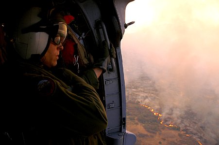 US Navy 071023-N-3069F-001 Chief Aviation Electronics Technician Rexford Sackett, assigned to Helicopter Sea Combat Squadron (HSC) 85, looks upon miles of burnt terrain as he and other Sailors prepare to help fend off the blaze