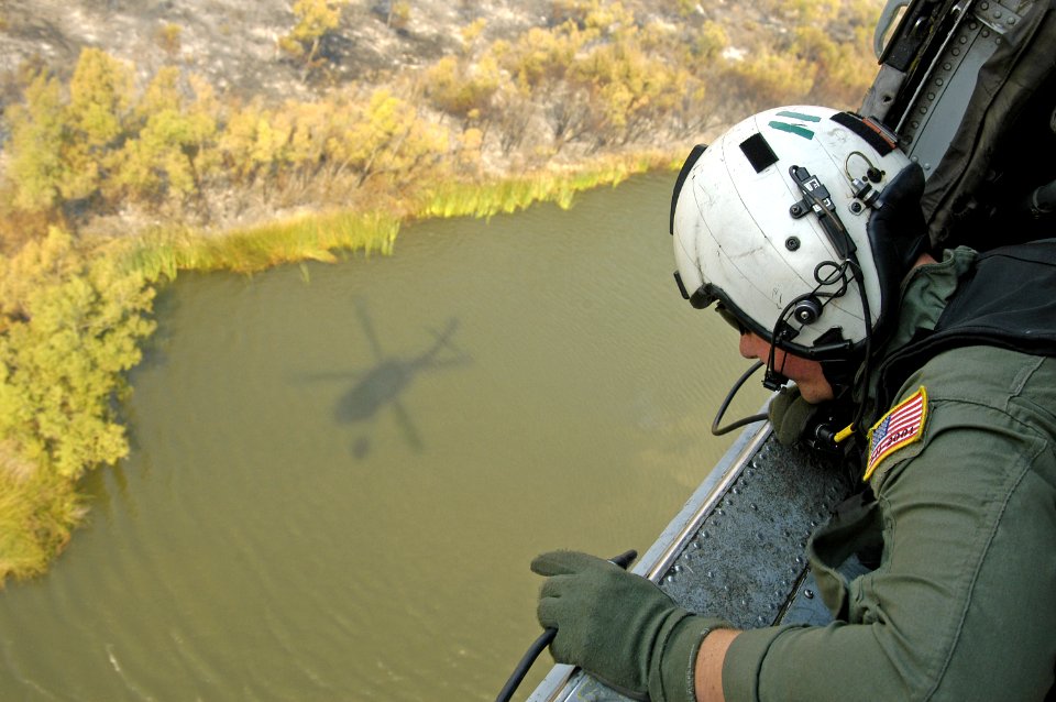 US Navy 071024-N-6597H-021 Aviation Warfare Systems Operator 2nd Class Danny Vickers helps guide pilots while scooping water from a lake near the wild fires in San Diego