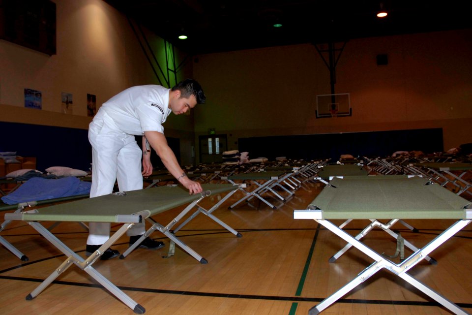 US Navy 071023-N-5086M-023 Culinary Specialist 2nd Class Yan Ng prepares cots for potential evacuees during the San Diego wildfires, which have already burned more than 250,000 acres in San Diego County