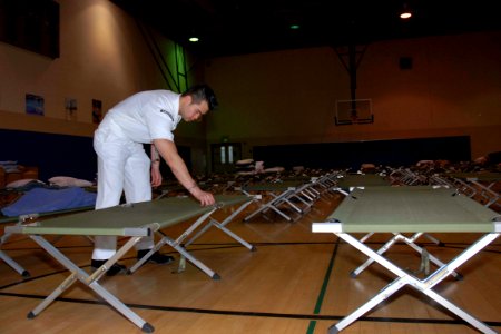 US Navy 071023-N-5086M-023 Culinary Specialist 2nd Class Yan Ng prepares cots for potential evacuees during the San Diego wildfires, which have already burned more than 250,000 acres in San Diego County