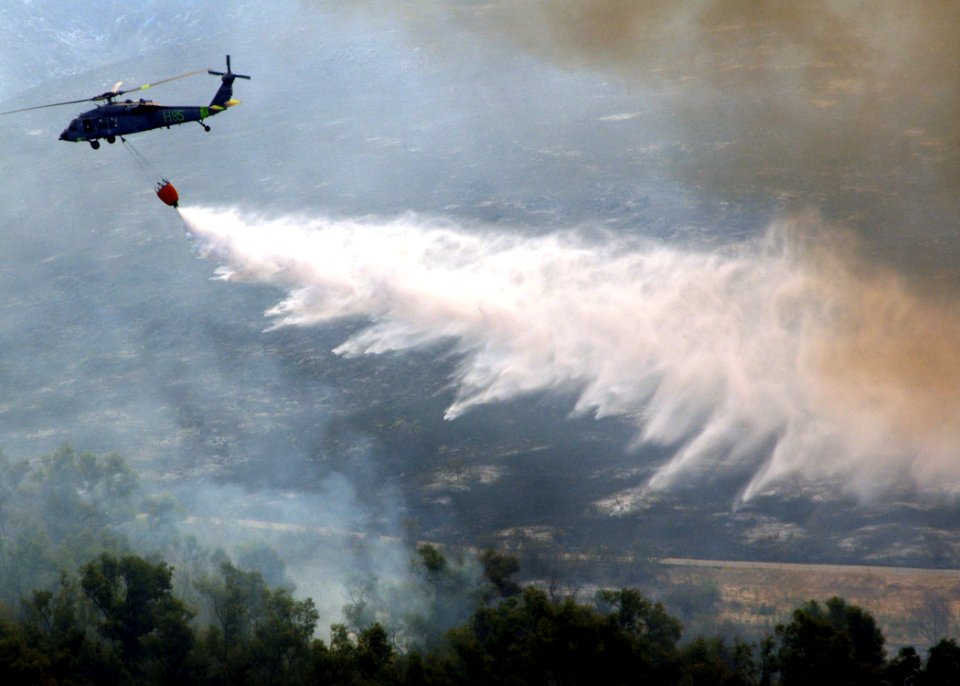 US Navy 071023-N-3069F-006 An MH-60S Seahawk assigned to Helicopter Sea Combat Squadron (HSC) 85, dumps water from a full 420-gallon extinguishing trough onto of one of the many areas in San Diego County suffering from an ongoi