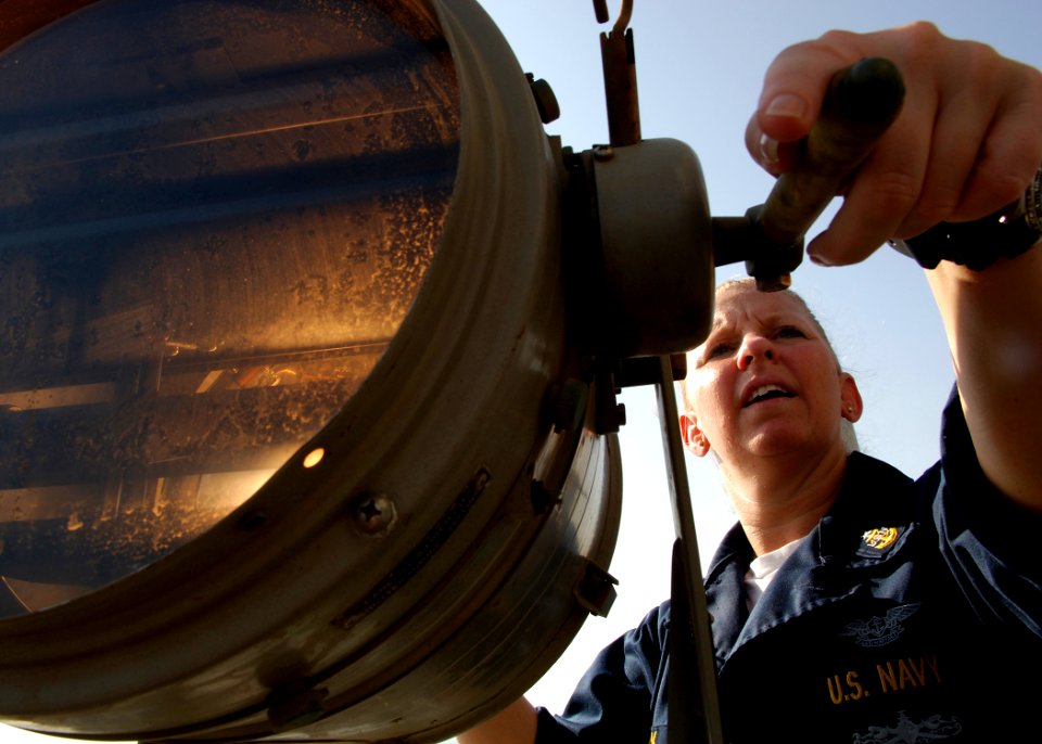 US Navy 071029-N-5928K-002 Senior Chief Quartermaster Melissa Black uses a searchlight from the signal bridge of nuclear-powered aircraft carrier USS Enterprise (CVN 65) to establish visual communications with guided-missile c