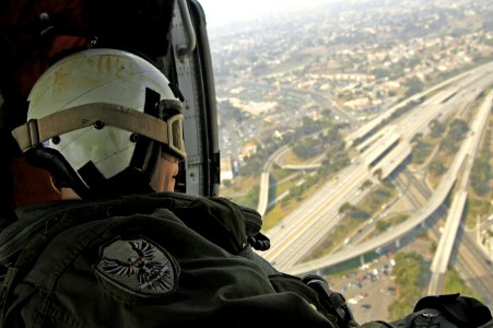 US Navy 071024-N-6597H-004 Aviation Warfare Systems Operator 2nd Class William Frost observes the view from an MH-60S Seahawk helicopter on his way to help fight the fires in San Diego