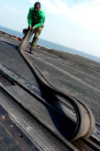 US Navy 071026-N-8132M-007 Aviation Boatswain's Mate (Equipment) 3rd Class Wilbert Charles removes the slot seals from a catapult on the flight deck of nuclear-powered aircraft carrier USS Enterprise (CVN 65)