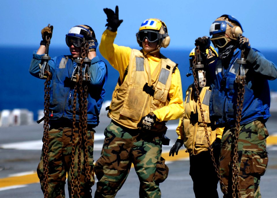 US Navy 090625-N-9950J-185 Sailors aboard the amphibious assault ship USS Essex (LHD 2) signal to a helicopter pilot before launching a CH-46E Sea Knight helicopter