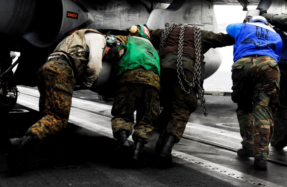 US Navy 090626-N-7780S-048 Sailors and Marines push an F-A-18C Hornet from assigned to the Death Rattlers of Marine Strike Fighter Squadron (VMFA) 323 into place after flight operations aboard the aircraft carrier USS John C. S