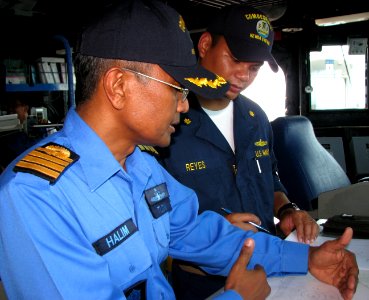 US Navy 090627-N-7058E-188 Royal Malaysian Navy Capt. Halim Bin Maulud observes at-sea maneuvering exercises with Lt. Cmdr. Ronel Reyes of Commander, Task Group 73.5 on the bridge of the dock landing ship USS Harpers Ferry (LSD