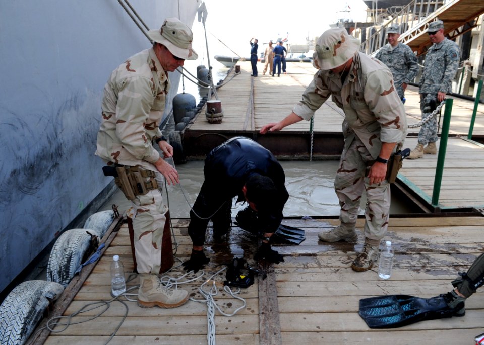US Navy 090701-N-6814F-217 Navy Diver 2nd Class Greg Early climbs out of the water with assistance from Chief Warrant Officer 2 Gary Hakes, and Senior Chief Navy Diver Craig Simon after completing a dive