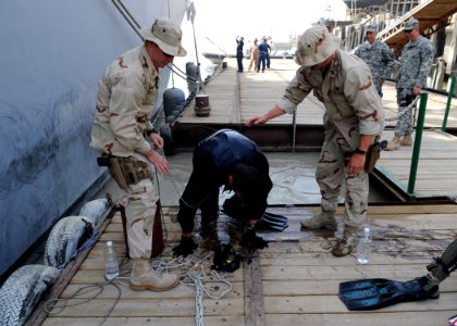 US Navy 090701-N-6814F-217 Navy Diver 2nd Class Greg Early climbs out of the water with assistance from Chief Warrant Officer 2 Gary Hakes, and Senior Chief Navy Diver Craig Simon after completing a dive