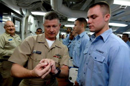 US Navy 090702-N-9818V-208 Master Chief Petty Officer of the Navy (MCPON) Rick West, left, gives Boatswain's Mate Seaman Brett Kish his Enlisted Surface Warfare Specialist pin during an awards ceremony aboard the USS John S. Mc