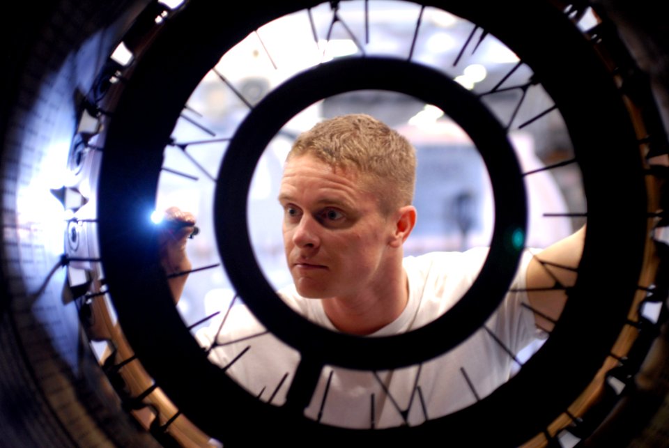 US Navy 090703-N-9132C-166 Aviation Machinist's Mate 2nd Class Steven Aldridge inspects the after burner of a F404 engine in the jet shop aboard the aircraft carrier USS Ronald Reagan (CVN 76)