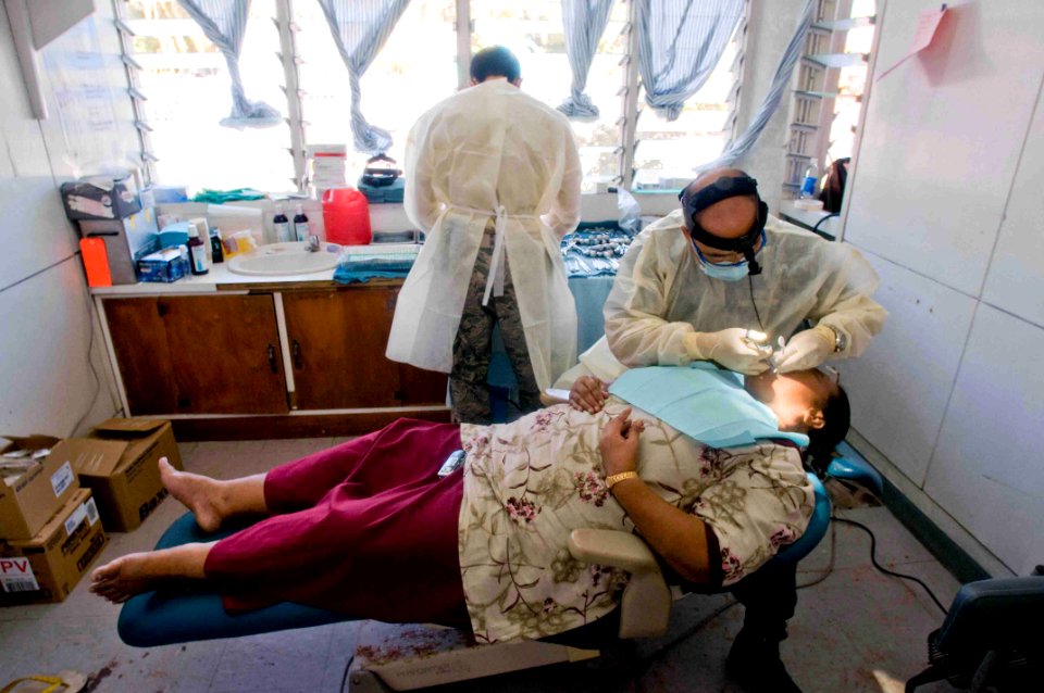 US Navy 090703-N-9689V-004 U.S. Navy Cmdr. Joseph Yang and U.S. Air Force Senior Airman Augustine Godinet perform a dental examination on a local woman