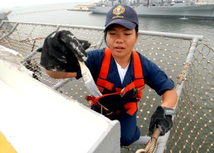 US Navy 090706-N-6439C-025 Midshipman 3rd Class Jade Surela Prudente, from the U.S. Naval Academy, paints the side of the scuppers on the flight deck of the amphibious assault ship USS Nassau (LHA 4)