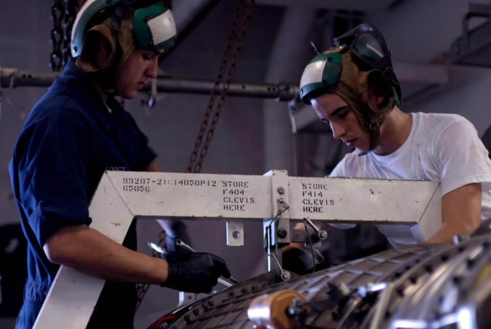US Navy 090703-N-9132C-067 Aviation Machinist's Mate Airman Jesus Lopez and Aviation Machinist's Mate Airman Wayne Kirkfield loosen the top half of the combustor of a F404 engine so maintenance can be preformed