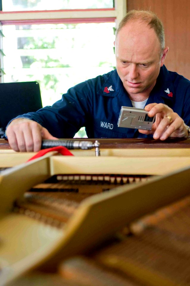 US Navy 090705-N-9689V-003 Musician 1st Class Jeremy Ward, assigned to the Pacific Fleet Band, tunes a piano at the house of what might one day become the Samoan national orchestra during a Pacific Partnership 2009 community se