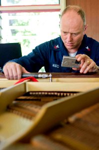 US Navy 090705-N-9689V-003 Musician 1st Class Jeremy Ward, assigned to the Pacific Fleet Band, tunes a piano at the house of what might one day become the Samoan national orchestra during a Pacific Partnership 2009 community se