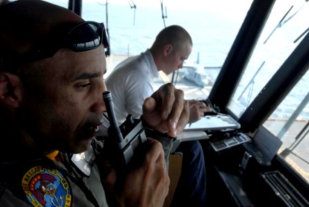 US Navy 090707-N-3592S-105 Cmdr. Gregg Romero, air boss aboard the amphibious assault ship USS Nassau (LHA 4), radios commands to aircraft handlers from primary flight control to the flight deck