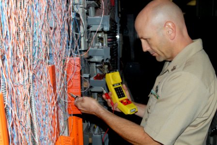 US Navy 090709-N-2143T-002 Electronics Technician 1st Class Harold Duffey from Port Orchard, Wash., tests phone lines with a phone tester