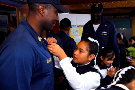 US Navy 090710-N-7092S-110 A student from Escuela General Basica Centenario pins a welcome card to Command Master Chief David Graham from guided-missile frigate USS Kauffman (FFG 59), during a community relations project in Ari