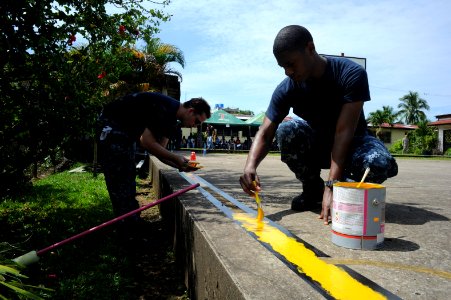 US Navy 100920-N-9964S-048 Quartermaster 2nd Class Shawn Dekle and Fireman Christopher Thomas paint a yellow line on a basketball court during a co