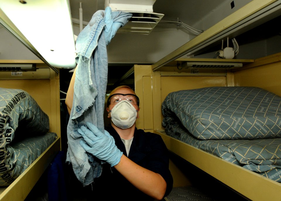 US Navy 100922-N-1092P-025 Seaman Amanda Carlton cleans the air-conditioning vents in a berthing compartment aboard the Nimitz-class aircraft carri