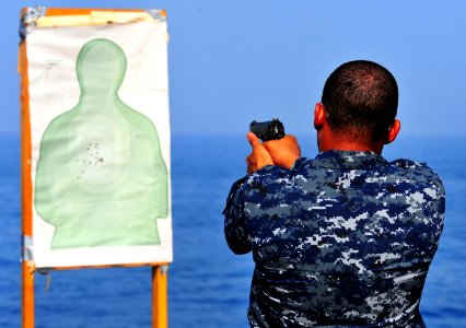 US Navy 100917-N-7948R-102 Navy Counselor 1st Class Khafre Quintall fires a 9mm handgun during small arms training aboard the amphibious dock landi photo