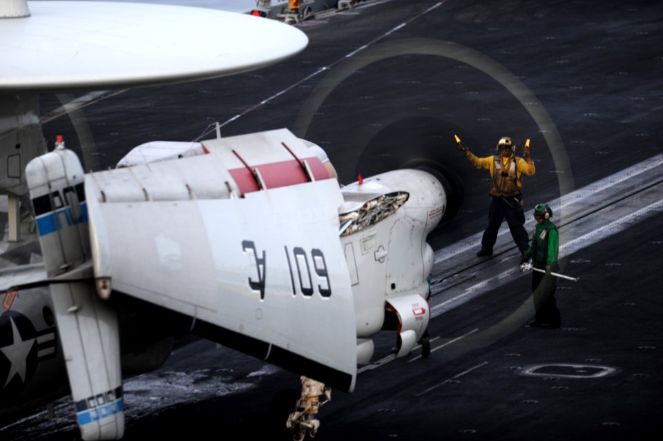 US Navy 100918-N-6427M-256 A flight deck plane director lines up an E-2C Hawkeye for launch during night flight operations aboard the aircraft carr