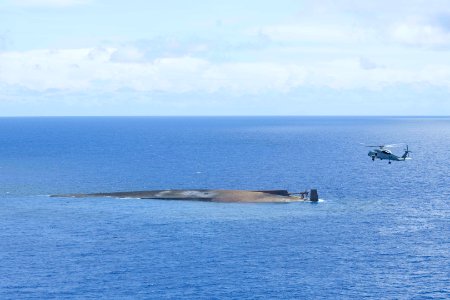 US Navy 100920-N-6720T-214 The Yellowstone-class destroyer tender Ex-USS Acadia (AD 42) floats capsized off the coast of Guam as an HH-60H Sea Hawk