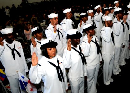 US Navy 100920-N-6632S-068 Sailors raise their right hands while reciting the oath of citizenship during a naturalization ceremony in the hangar ba