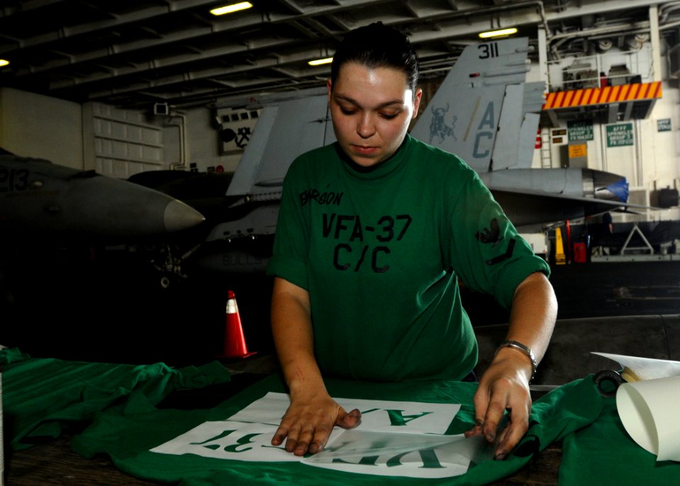 US Navy 100921-N-1092P-102 Aviation Structural Mechanic 3rd Class Jessica May Emerson stencils flight deck jerseys in the hangar bay of the Nimitz