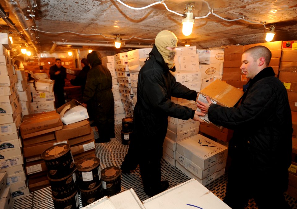 US Navy 100923-N-6362C-036 Damage Controlman Fireman Josh Steiger hands a frozen goods package to Electrician's Mate 3rd Class Joseph Spangenberg i