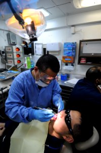 US Navy 100920-N-7191M-022 Hospital Corpsman 1st Class Gustavo Aragones, from Sacramento, Calif., performs a routine dental cleaning on Yeoman 3rd