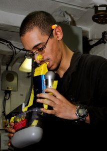 US Navy 100927-N-3729D-096 Machinist's Mate Fireman Aleric Hernandez dons an emergency escape breathing device during engineering training evolutio photo