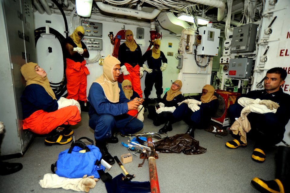 US Navy 101001-N-8335D-058 Boatswain's Mate 2nd Class Carlglo Rula, center, teaches Sailors how to patch a cracked pipe using the banding method du
