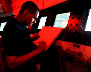 US Navy 100925-N-3793B-166 Seaman Robert A. Torralva records an entry in a logbook during his watch in a conflagration station aboard USS Harry S