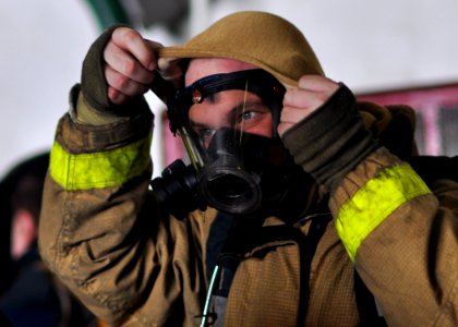 US Navy 100930-N-2013O-018 A Sailor adjusts his flash hood after donning his firefighting ensemble during a mass casualty drill in the hangar bay o