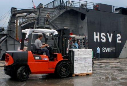 US Navy 100927-N-4971L-053 Hugh Grandstaff, third mate aboard High Speed Vessel Swift (HSV 2), moves a pallet of Project Handclasp Relief supplies photo