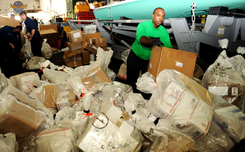 US Navy 100923-N-6362C-112 Logistics Specialist 2nd Class Michael Bell sorts through bags of mail in the hangar bay aboard the aircraft carrier USS