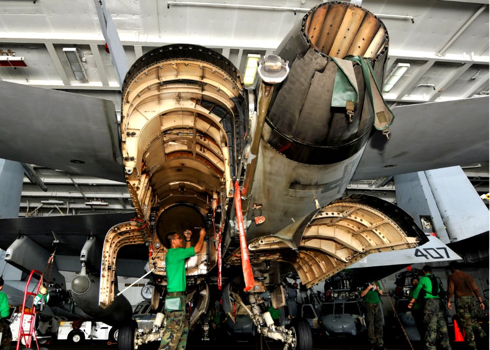 US Navy 100929-N-7103C-019 Aviation Structural Mechanic (Equipment) Airman Frederick Copuyoc removes bolts from the access panel of an F-A-18C Horn