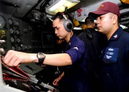 US Navy 100927-N-3729D-104 Electrician's Mate 2nd Class Ryan Manalo, left, conducts an electrical ground test under the supervision of Electrician' photo