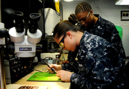 US Navy 100929-N-4135M-049 Electronics Technician 3rd Class Viola Simmons trains Electronics Technician 3rd Class Chauntel Broughton how to solder