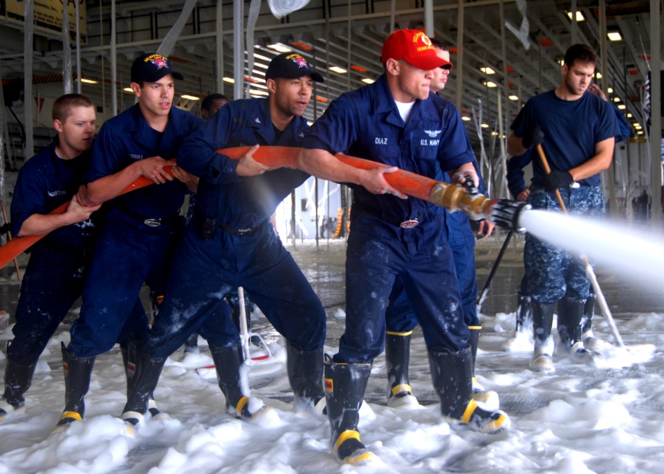 US Navy 100929-N-3495P-129 Sailors wash down the deck after an aqueous film forming foam (AFFF) systems check in the hangar bay aboard the amphibi