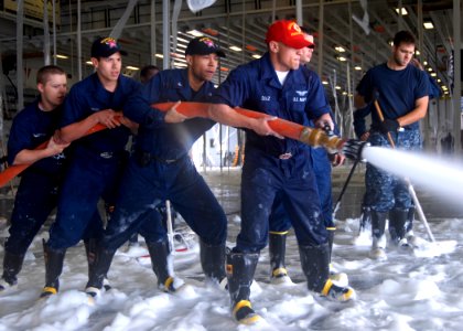 US Navy 100929-N-3495P-129 Sailors wash down the deck after an aqueous film forming foam (AFFF) systems check in the hangar bay aboard the amphibi