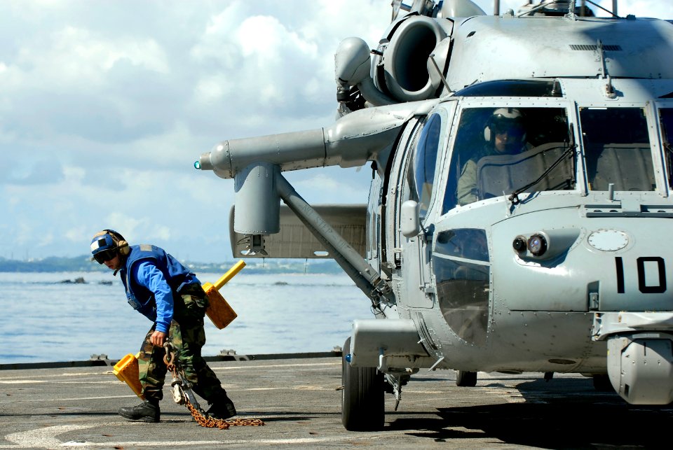 US Navy 101003-N-8335D-199 Seaman Michael Tarquino runs for safety after removing a chock and chain from the wheel of an MH-60S Sea Hawk helicopter