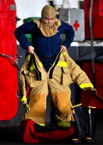US Navy 100930-N-2013O-007 A Sailor dons firefighting coveralls during a mass casualty drill in the hangar bay of the aircraft carrier USS George