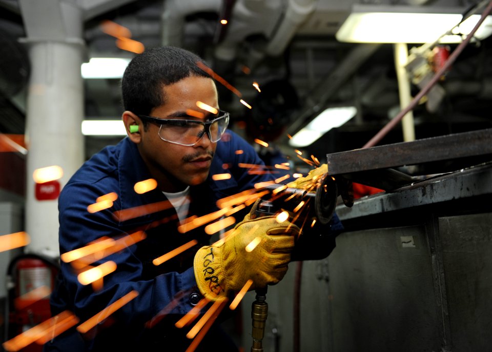 US Navy 101006-N-6427M-078 Hull Maintenance Technician Fireman Ruben Torres of Bloomington, Ind., grinds down excess welds during the fabrication o