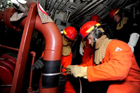 US Navy 101005-N-8335D-011 Operations Specialist 3rd Class Nicholas Maloney applies a banding patch to a simulated ruptured pipe during a general q